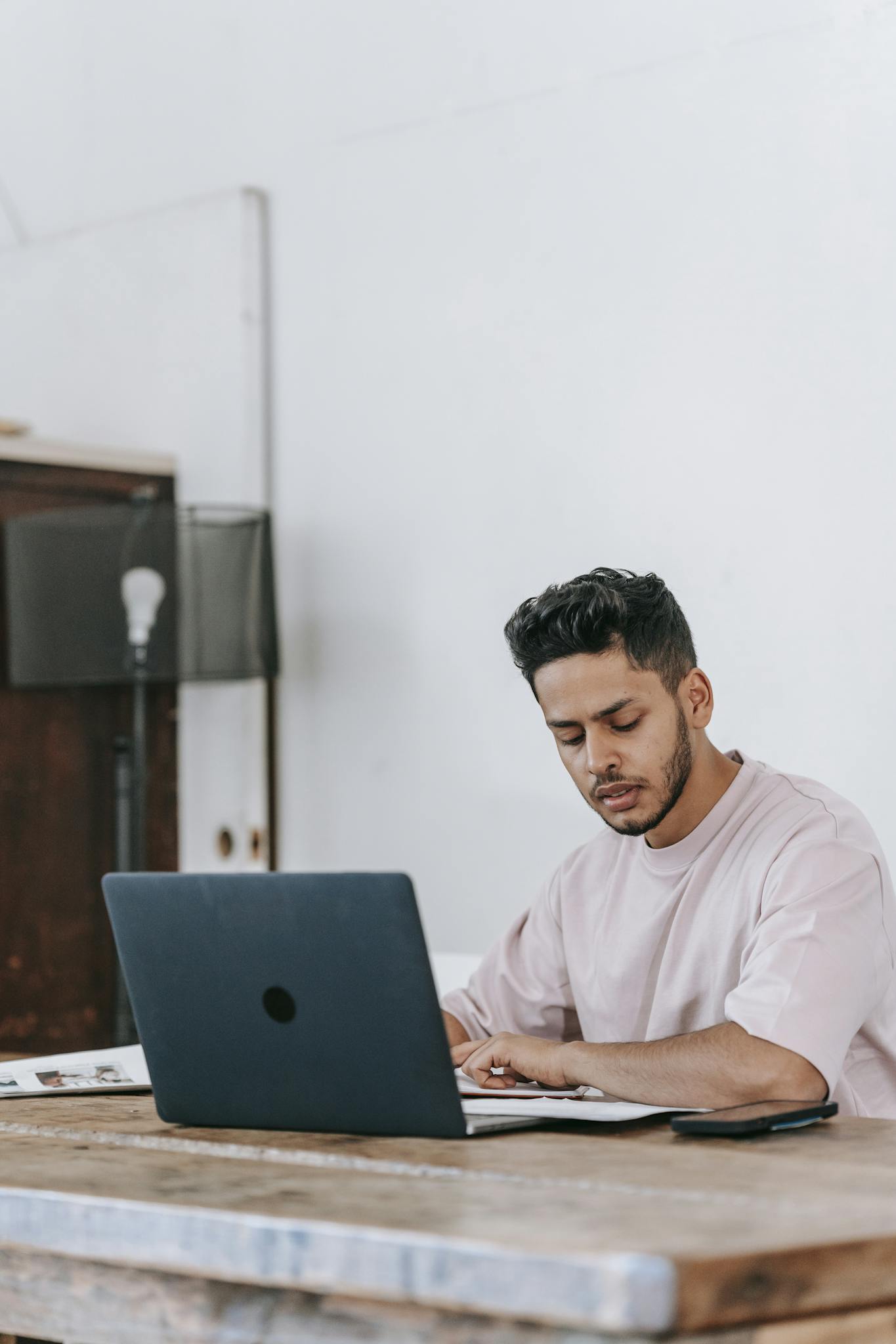A young man concentrates on his laptop while working from home, embodying modern freelance life.
